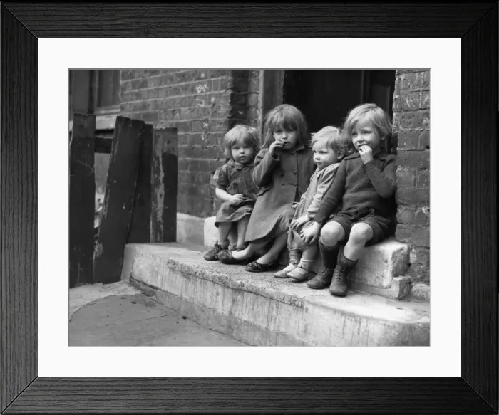 Framed Print : Young children sitting on the doorstep of one of their homes Doris Street, London