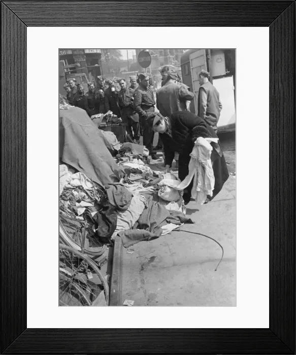 Framed Print : A woman laying down spare clothes at a collection point to be used for others who need