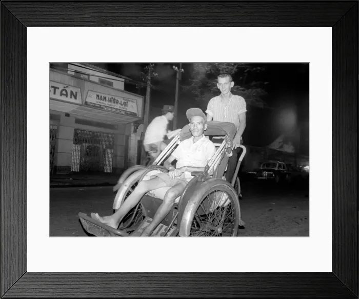 Framed Print : Night life in Saigon Vietnam. Young man pushes another man in a type of rickshaw Framed Print : Night life in Saigon Vietnam. Young man pushes another man in a type of rickshaw