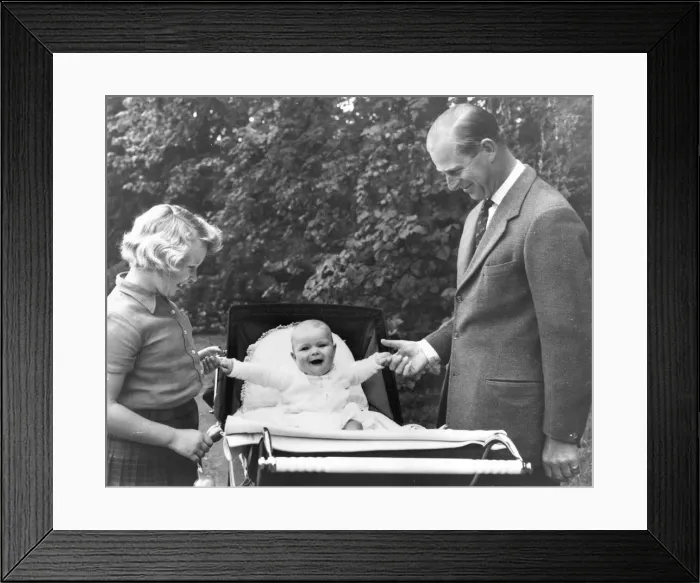 Framed Print : Prince Andrew laughs while sitting in his pram as he grips the finger of his father
