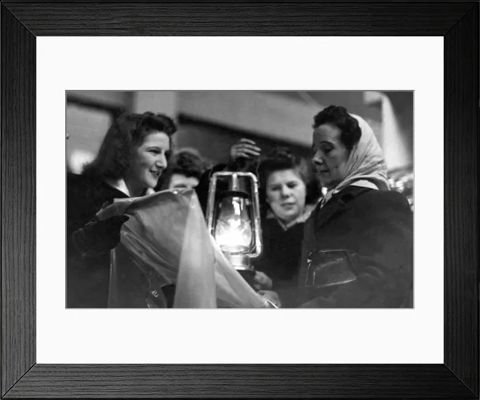 Framed Print : A customer in the Newcastle Grainger Market examines a rain coat by the lift of an oil Framed Print : A customer in the Newcastle Grainger Market examines a rain coat by the lift of an oil