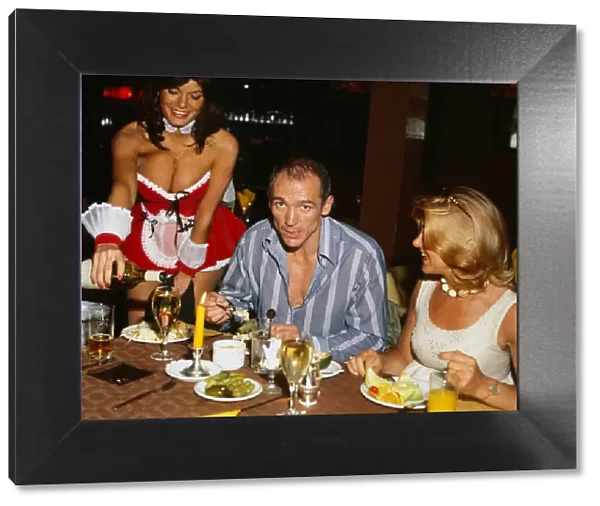 John McVicar August 1980 sitting at table eating with bunny girl serving him wine