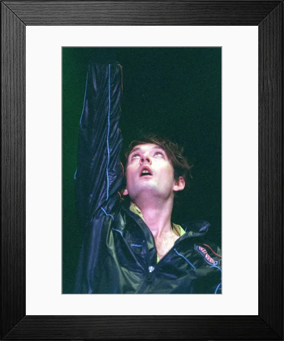 Framed Print : Jarvis Cocker of pop group Pulp on stage at T in the Park on Sunday with arm raised in
