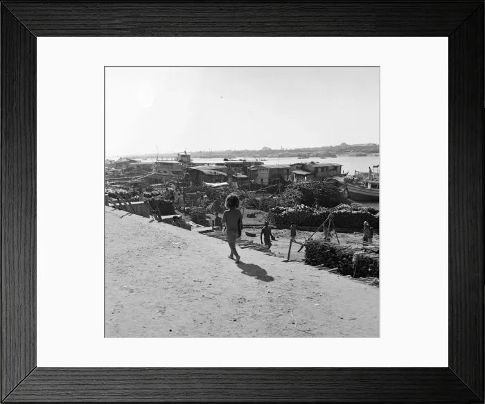 Framed Print : A child watches the boats unloaded in Dacca, Bangladesh. February 1961 l Framed Print : A child watches the boats unloaded in Dacca, Bangladesh. February 1961 l