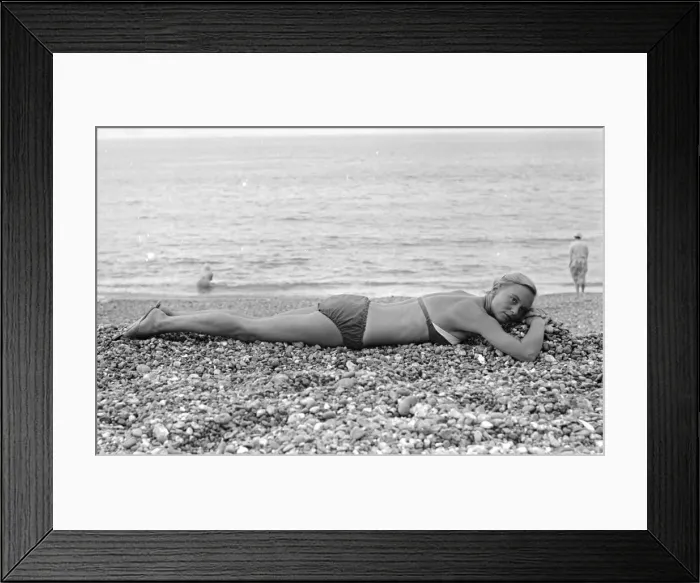 Framed Print : A woman sunbathing on the pebble beach at Brighton July 1958