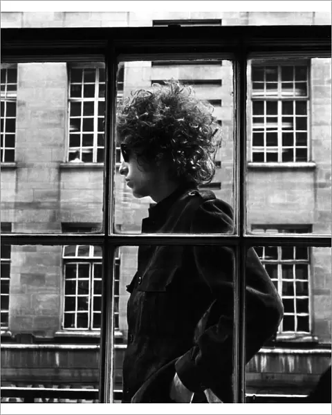 The one and only Bob Dylan pictured walking past a shop window in London, 3rd May 1966