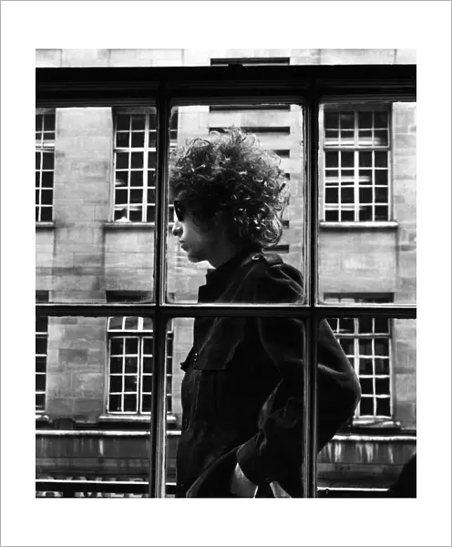 The one and only Bob Dylan pictured walking past a shop window in London, 3rd May 1966
