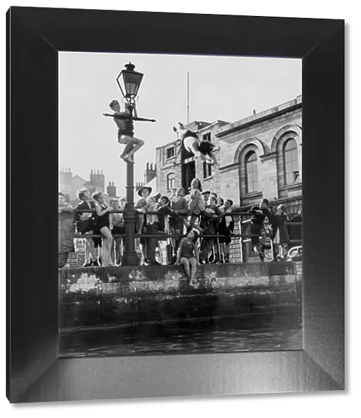 Summertime activities, children at Plymouth barbican diving if from a quayside lamp post