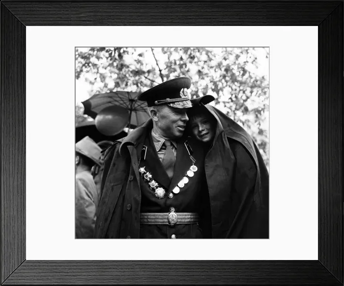 Framed Print : A soldier shelters his son from the rain under his greycoat during the May Day Framed Print : A soldier shelters his son from the rain under his greycoat during the May Day