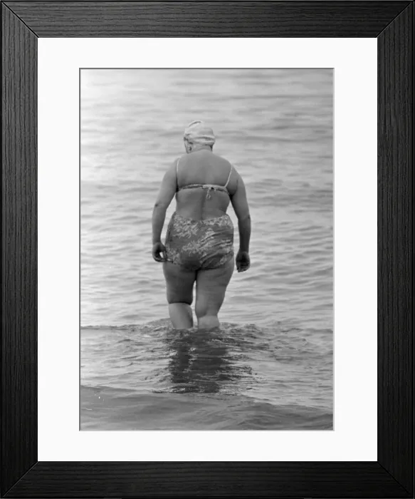 Framed Print : A woman goes for a swim in the sea on the beach at Brighton July 1958 Framed Print : A woman goes for a swim in the sea on the beach at Brighton July 1958