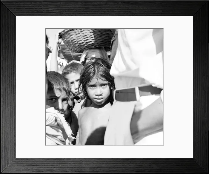 Framed Print : A young girl waits with her brothers and sister and the local traders wait to board a