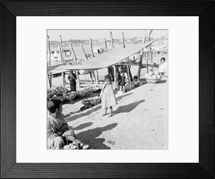 Framed Print : A child watches the market traders beside the harbour set up their stalls in Dacca Framed Print : A child watches the market traders beside the harbour set up their stalls in Dacca