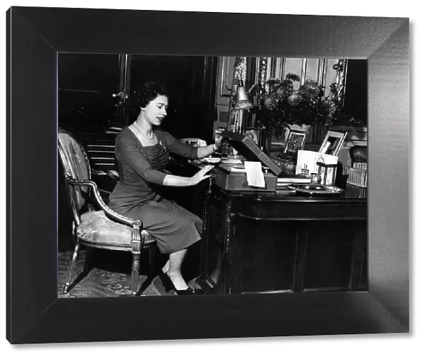 Queen Elizabeth II at her desk in Buckingham Palace looking through her correspondence