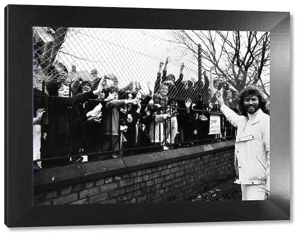 Barry Gibb of the Bee Gees pop group waves to children outside the gates of his former
