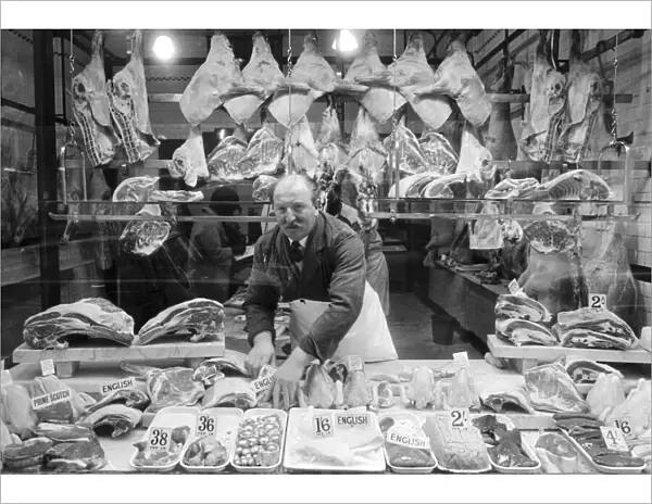 Butcher standing in his shop window, showing off his various meat products currently