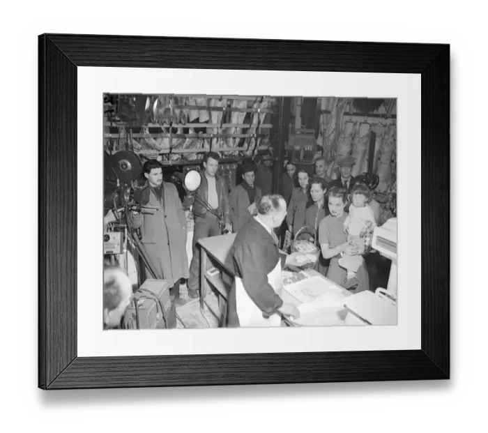 Framed Print : Film production company, filming a scene in a butchers shop as customers wait in long