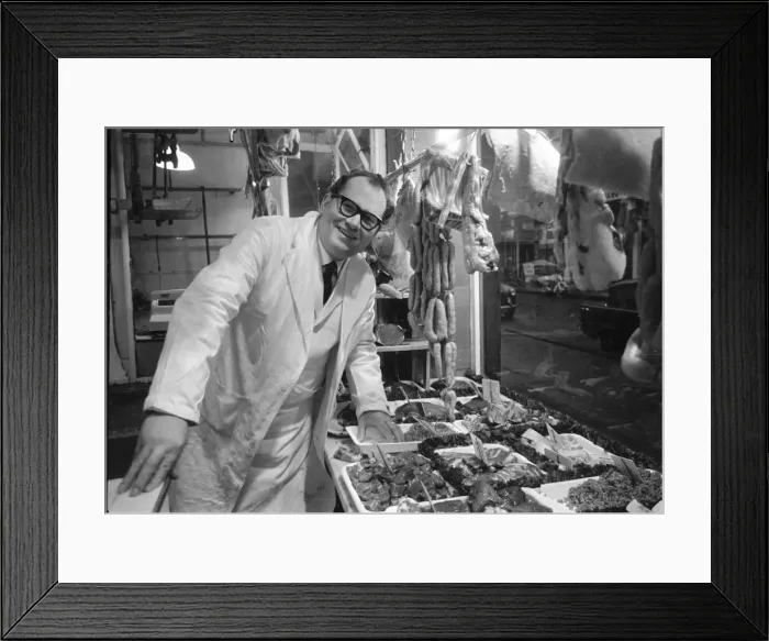 Framed Print : Butcher stands proudly in his shop as his various meat products are displayed in window Framed Print : Butcher stands proudly in his shop as his various meat products are displayed in window