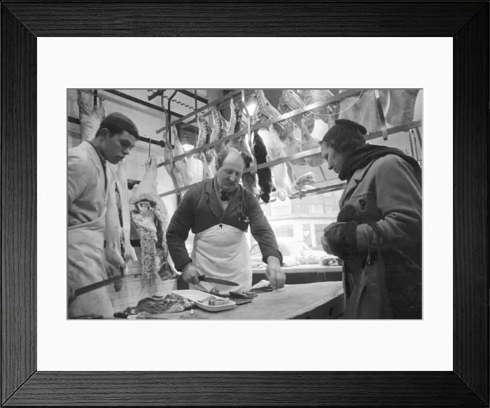 Framed Print : Butcher cuts up & cleans some lamb chops for woman customer Framed Print : Butcher cuts up & cleans some lamb chops for woman customer