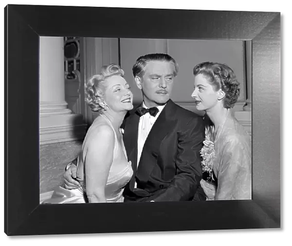 A man dressed in a smart evening suit with bow tie talking to two glamorous women at a