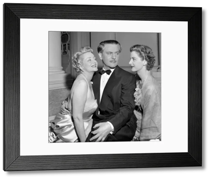 Framed Print : A man dressed in a smart evening suit with bow tie talking to two glamorous women at a
