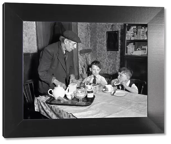 A man cutting up a fresh loaf of bread to serve his grandchildren at the breakfast table