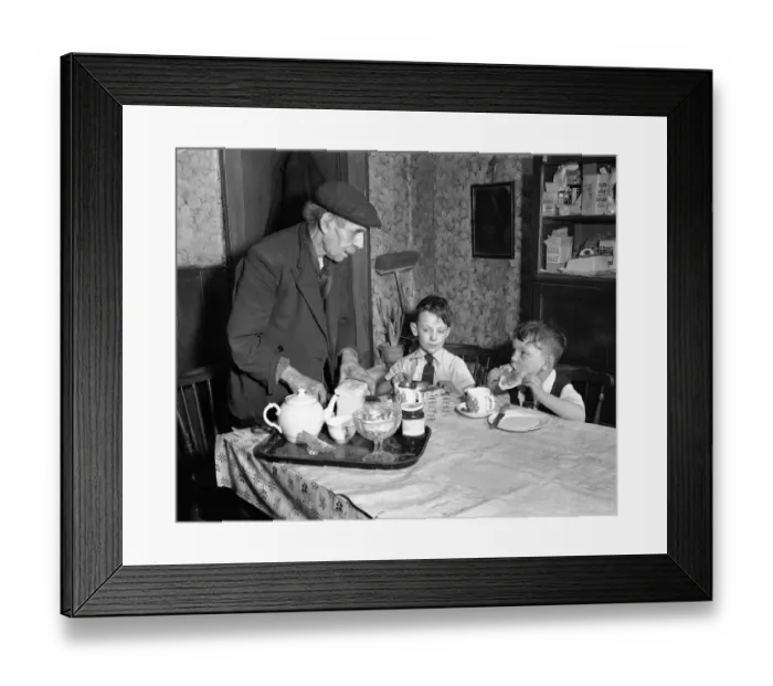 Framed Print : A man cutting up a fresh loaf of bread to serve his grandchildren at the breakfast table Framed Print : A man cutting up a fresh loaf of bread to serve his grandchildren at the breakfast table