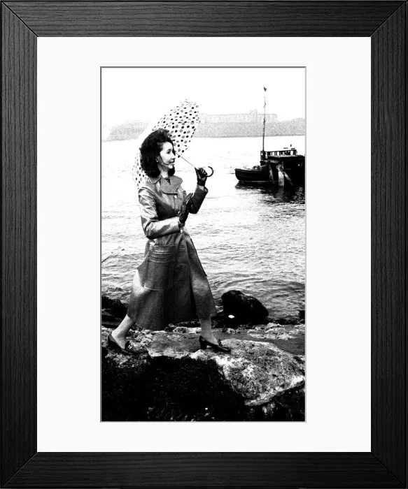 Framed Print : A model on the rocks at Tynemouth wearing a leather coat and umbrella in April 1970 Framed Print : A model on the rocks at Tynemouth wearing a leather coat and umbrella in April 1970