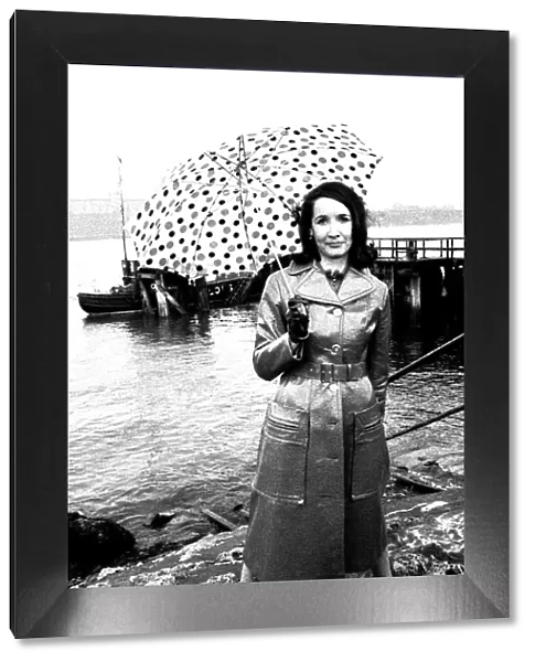 A model on the rocks at Tynemouth wearing a leather coat and umbrella in April 1970