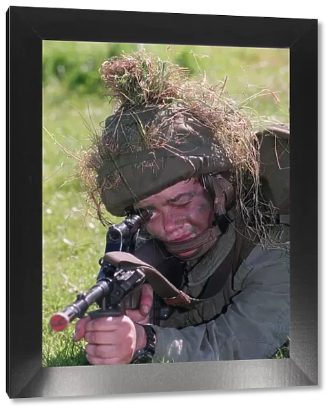February 1999 Soldier in camouflage with grass on his helmet laying on the ground