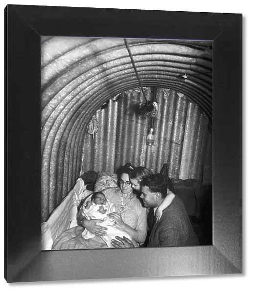 A family inside their air-raid shelter during WW2, with the mother cradling her new born