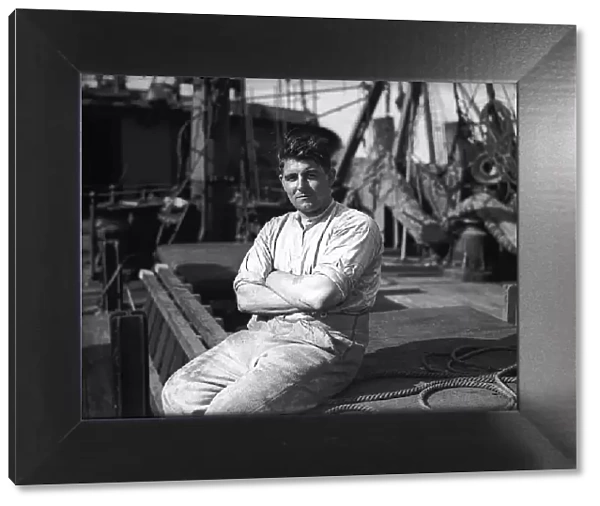 A merchant seaman in WW2 sitting on the deck of a ship. Circa 1941