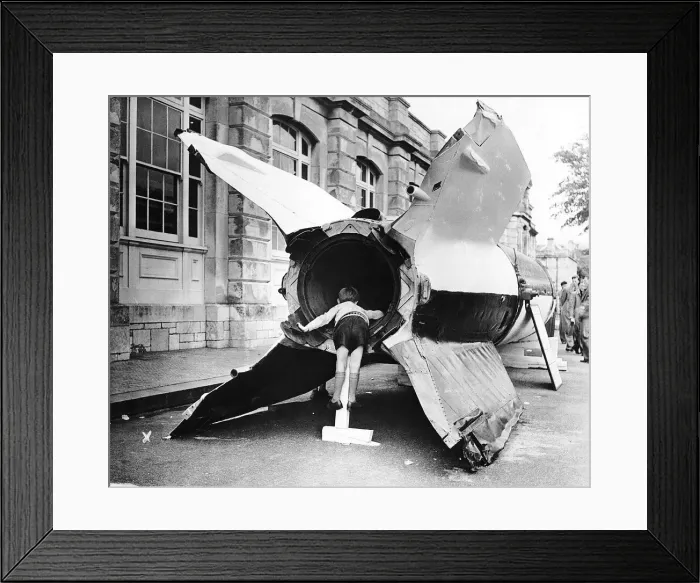 Framed Print : A young boy looks into the rocket motor of a captured V2 flying bomb during open day Framed Print : A young boy looks into the rocket motor of a captured V2 flying bomb during open day
