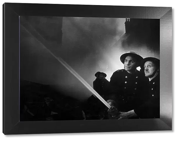 Firemen tackling fire after WW2 air raid on London. 1940s
