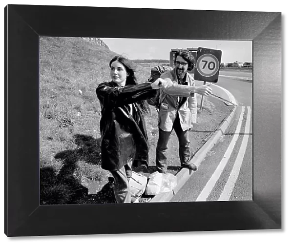 A young couple trying to hitch a lift on the motorway September 1970