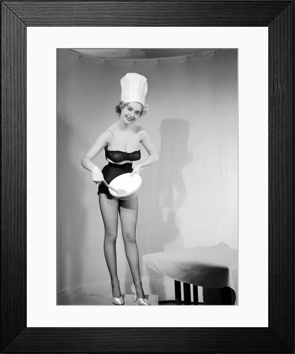 Framed Print : Woman modelling black lingerie and a chefs hat in a cooking photo shoot. Circa 1964