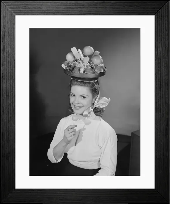 Framed Print : Model wearing a hat made from chocolate and fruit. Circa 1960 Framed Print : Model wearing a hat made from chocolate and fruit. Circa 1960