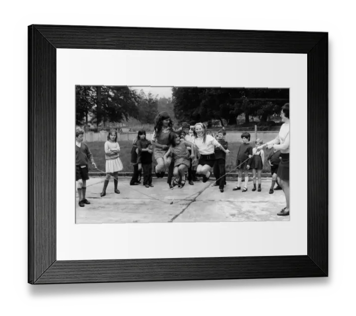 Framed Print : Young girl jumping over a skipping rope in the playground of the National School Framed Print : Young girl jumping over a skipping rope in the playground of the National School