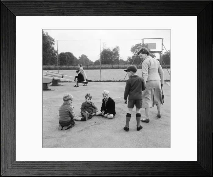 Framed Print : Children in the playground playing a game of marbles as one boy is dragged away by his Framed Print : Children in the playground playing a game of marbles as one boy is dragged away by his
