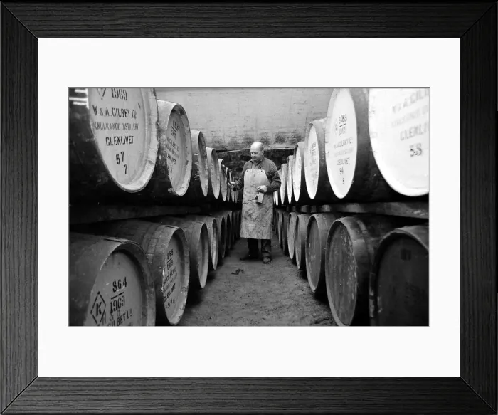 Framed Print : An employee of the Knockando Whisky Distillery in Scotland checks the casks in Framed Print : An employee of the Knockando Whisky Distillery in Scotland checks the casks in