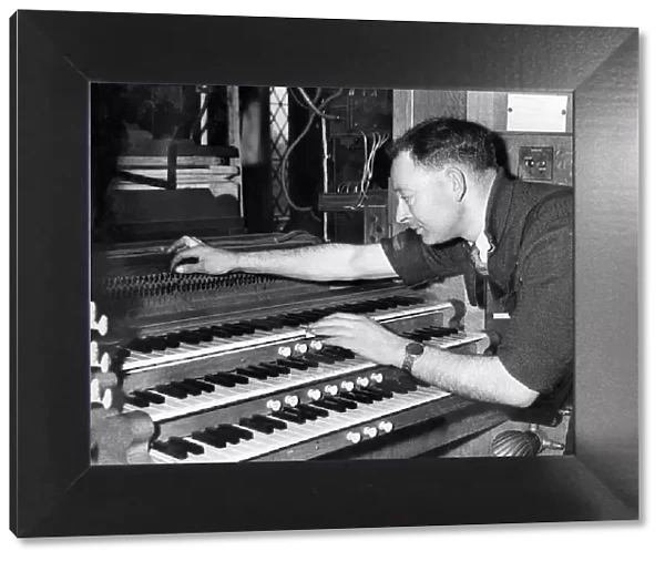 Mr. H. E. Prested test the action of an organ after re-assembly in May 1957
