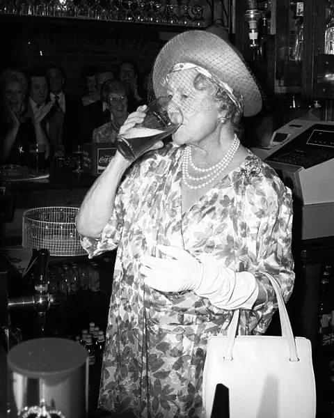 Queen Mother stands behind a pub bar drinking beer in July 1987