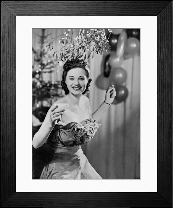 Framed Print : A woman enjoying a drink as she stands under the mistletoe at Christmas time A© Framed Print : A woman enjoying a drink as she stands under the mistletoe at Christmas time A©