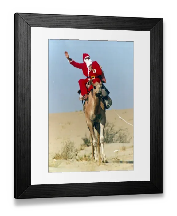 Framed Print : Santa Claus waves from atop his camel in the desert on his way to delivering a message to Framed Print : Santa Claus waves from atop his camel in the desert on his way to delivering a message to