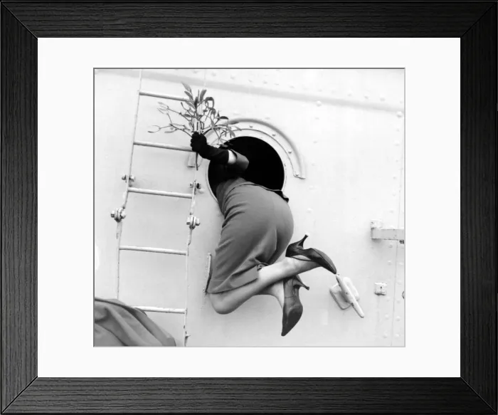 Framed Print : Beverley Janner holding mistletoe is pulled through a porthole by her sailor husband to Framed Print : Beverley Janner holding mistletoe is pulled through a porthole by her sailor husband to