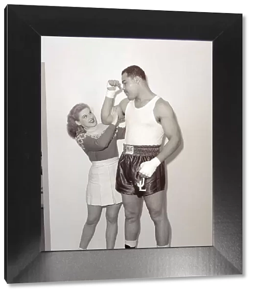Joe Louis with female model cheerleader feeling the size of his bicep at Earls Court