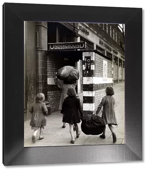 Children carrying bundles of laundry run towards the London Underground to take cover