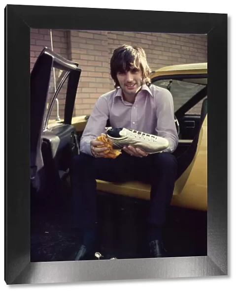 manchester United footballer George Best shows of his gold painted football boots which