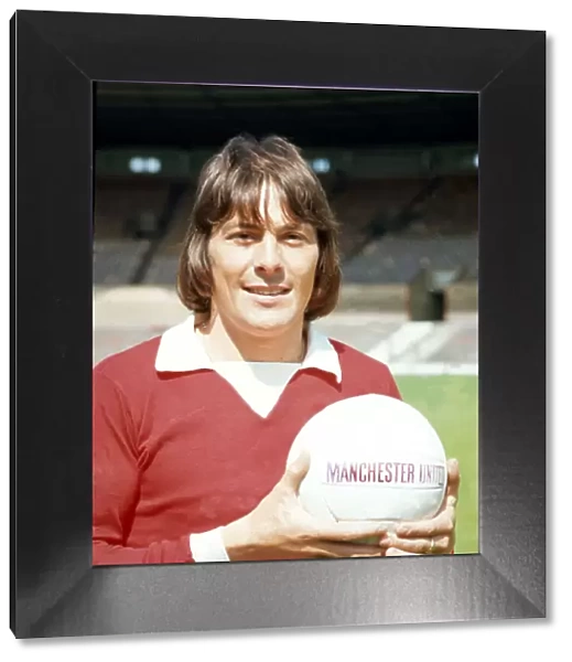 Manchester United footballer Stuart Pearson poses with the team football at Old Trafford