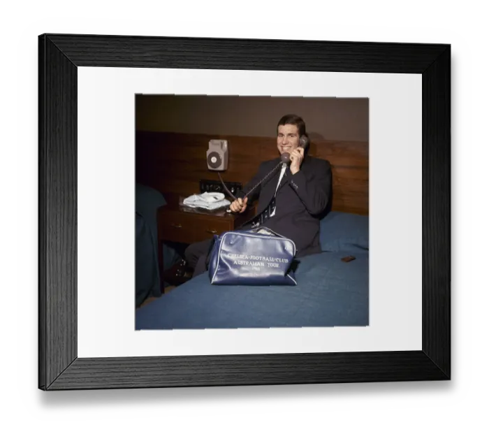 Framed Print : Chelsea footballer Peter Osgood on the telephone in his hotel room packing his bag Framed Print : Chelsea footballer Peter Osgood on the telephone in his hotel room packing his bag
