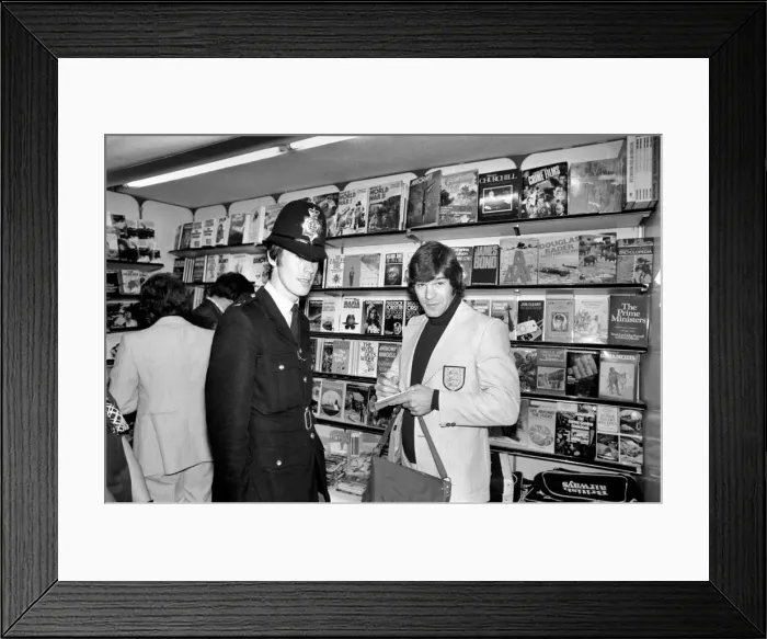 Framed Print : A policeman gets England footballer Malcolm MacDonalds autograph at Heathrow airport